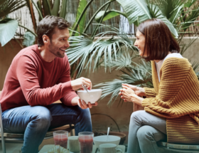 Image of a happy, smiling couple on a date together while the woman is looking out for signs he likes her.