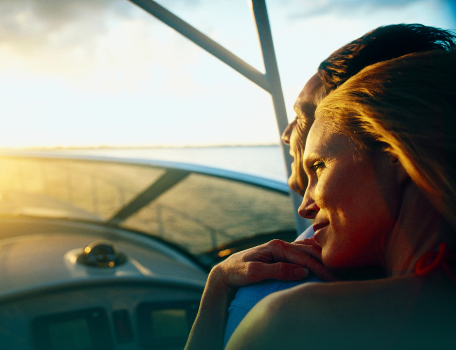 Smiling couple sitting in a boat and looking out to the sunset while enjoying a romantic date idea in Miami.
