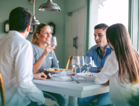 Two happy, smiling couples sitting around a table together drinking wine and enjoying of the best double date ideas.