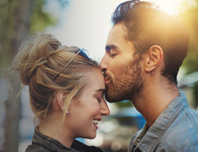 Man giving woman a kind kiss on the forehead at sunset