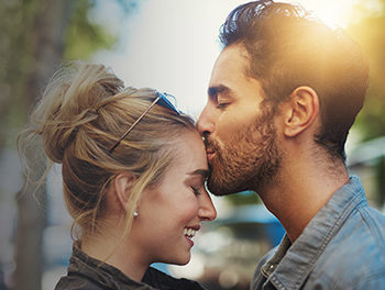 Man giving woman a kind kiss on the forehead at sunset