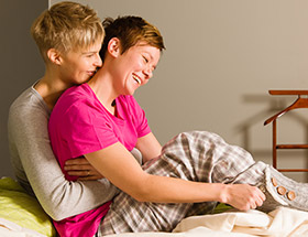 Lesbian couple cuddling in their pajamas after meeting on a lesbian dating app