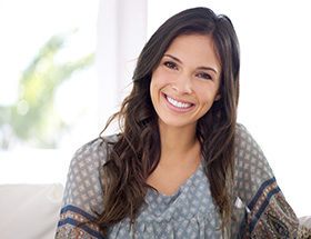 Young single woman sitting indoors and smiling and looking for real connections on an international dating platform.