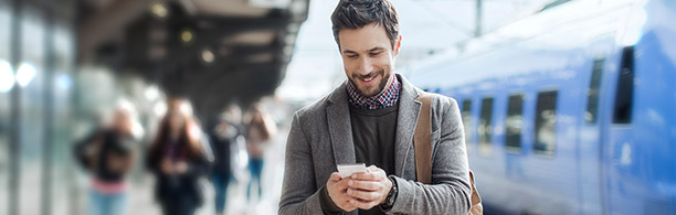 man at train station looking at phone