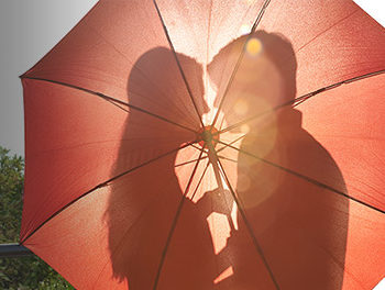 couple kissing behind red umbrella