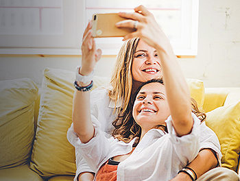 lesbian couple taking selfie on the sofa after reading advice on how to get a girlfriend as a girl