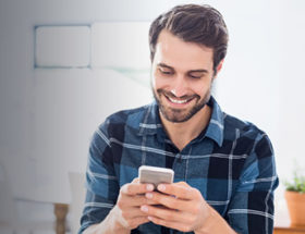 Happy gay man sending gay text messages on his smartphone
