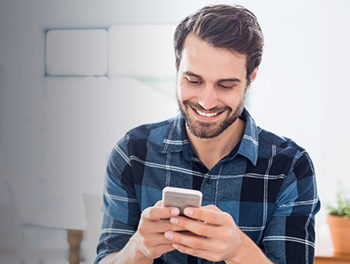 Happy gay man sending gay text messages on his smartphone