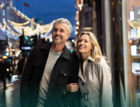 Smiling man and woman walking arm in arm while on a date together as the man thinks about some first date tips for guys.