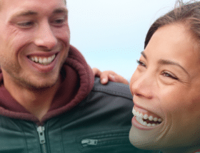 Happy, smiling couple standing in front of the Golden Gate Bridge while dating in California.