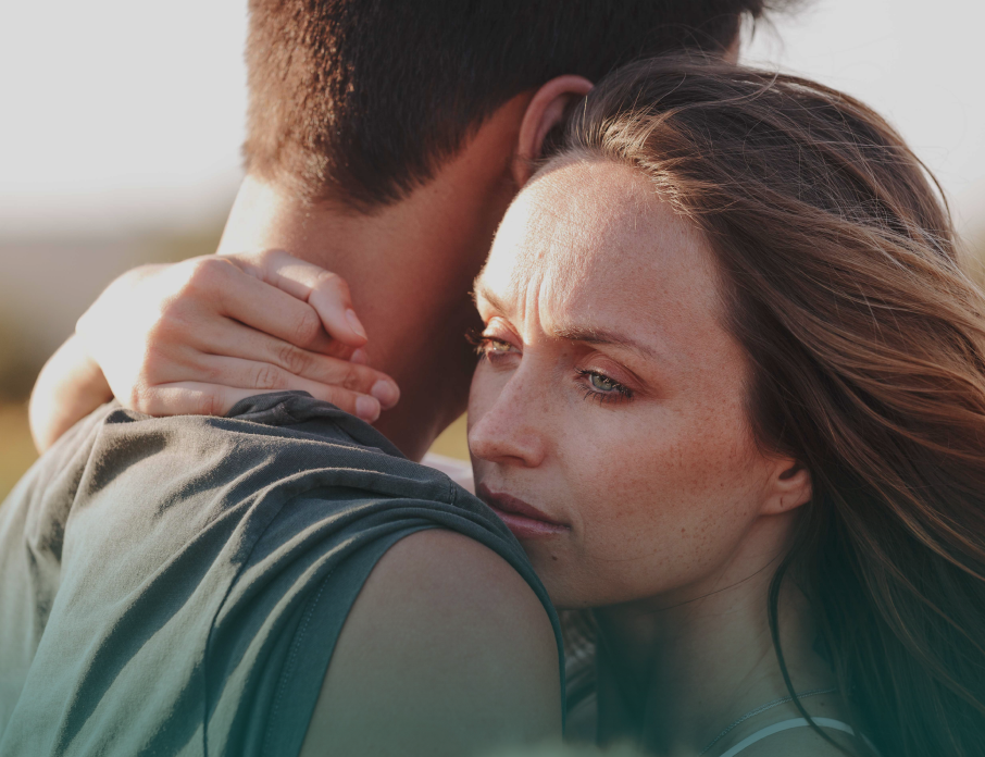 Woman hugging a man she's dating but looking worried and anxious after receiving mixed signals.